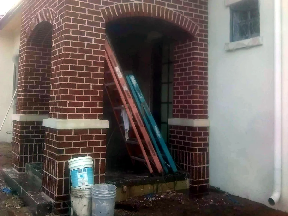 Arched brick entry with two brick arches, cast sills and brick columns on a house under construction, brick masonry
