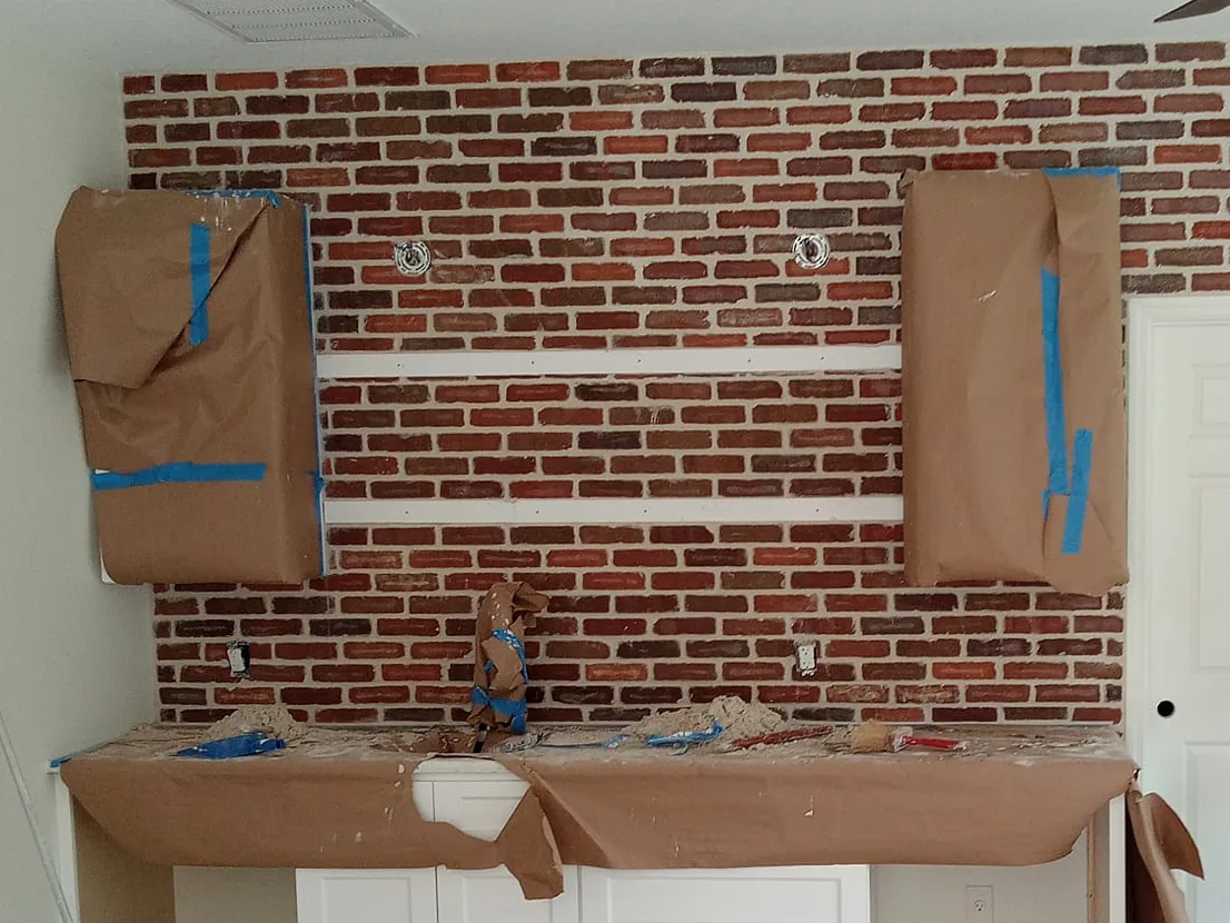 Interior brick wall before the whitewash, with the cabinets and counter wrapped in paper for protection, brick veneer