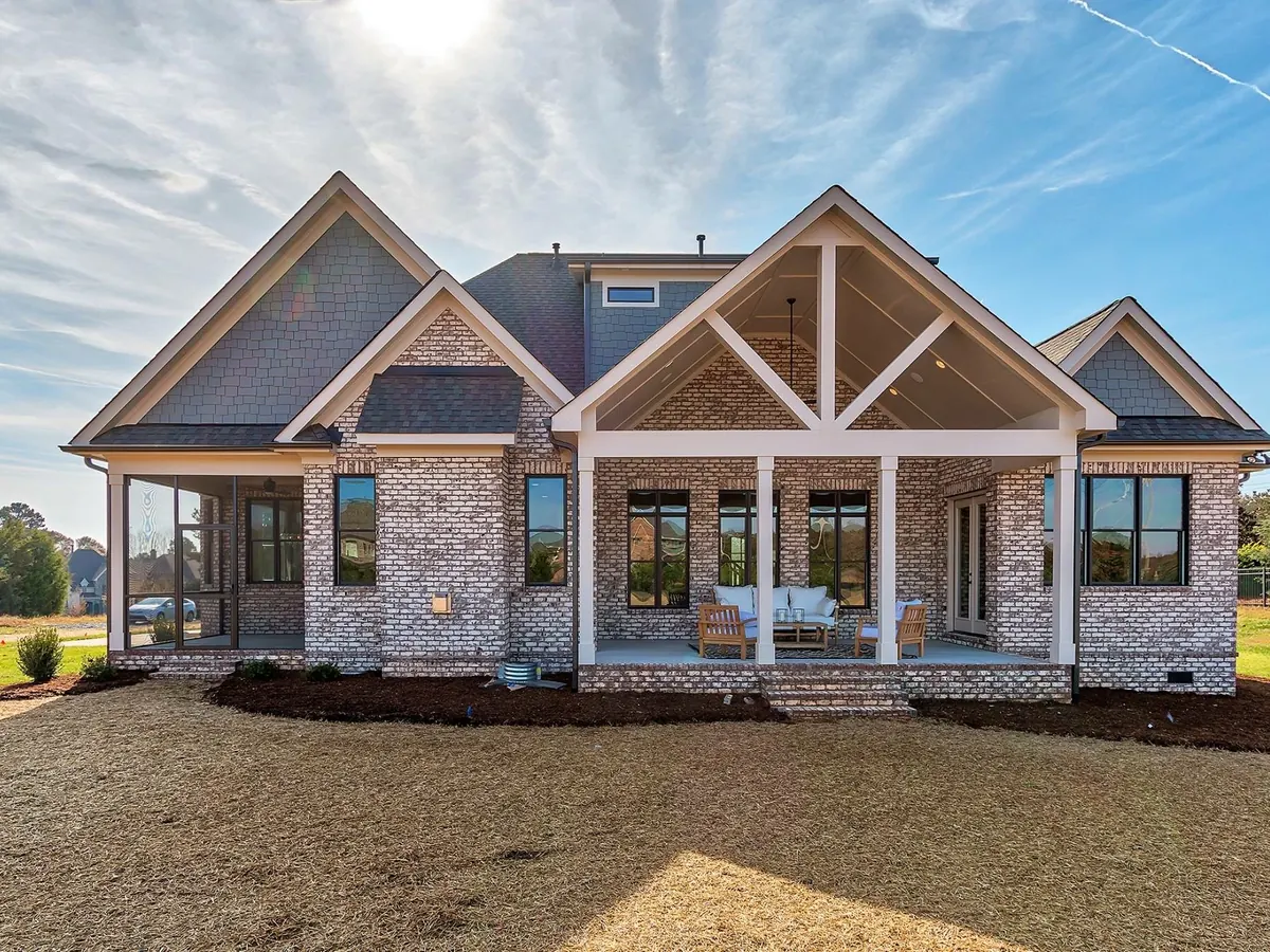 New one-and-a-half-story home finished in light brick veneer with a covered back porch, brick veneer