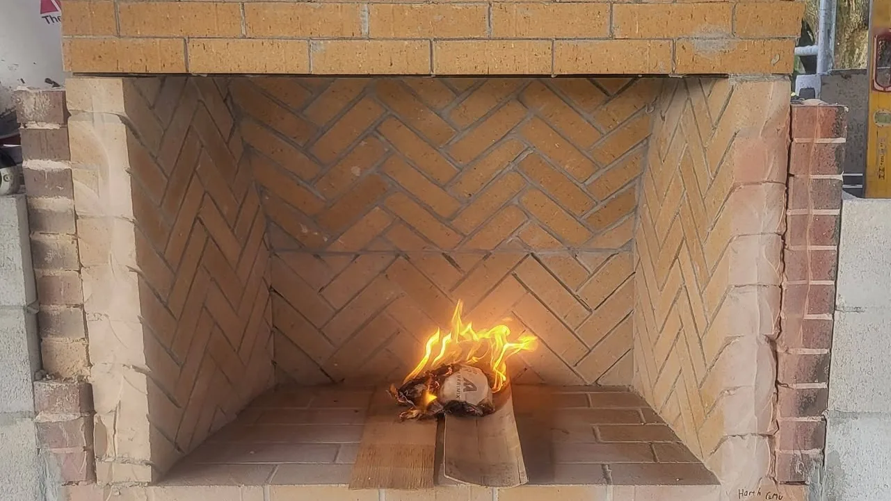 Fire burning in a new herringbone firebrick outdoor fireplace firebox, masonry