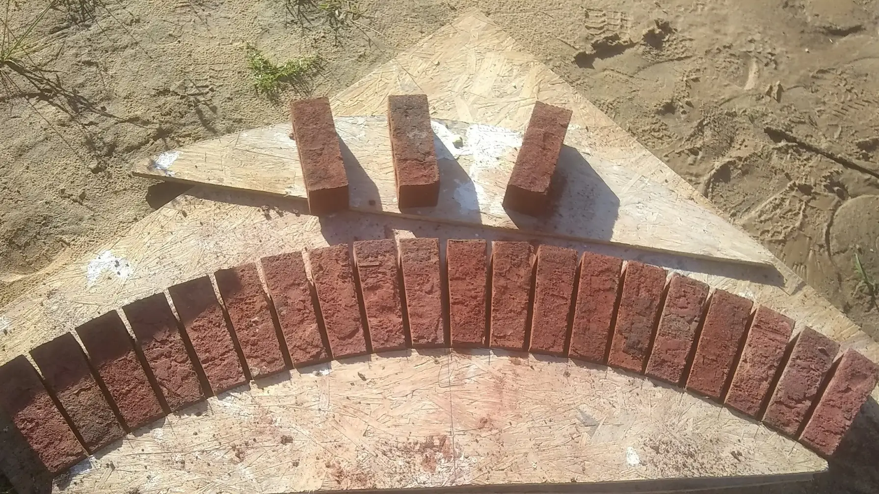Cut brick arch pieces laid out in a curve on a plywood arch template, brick masonry