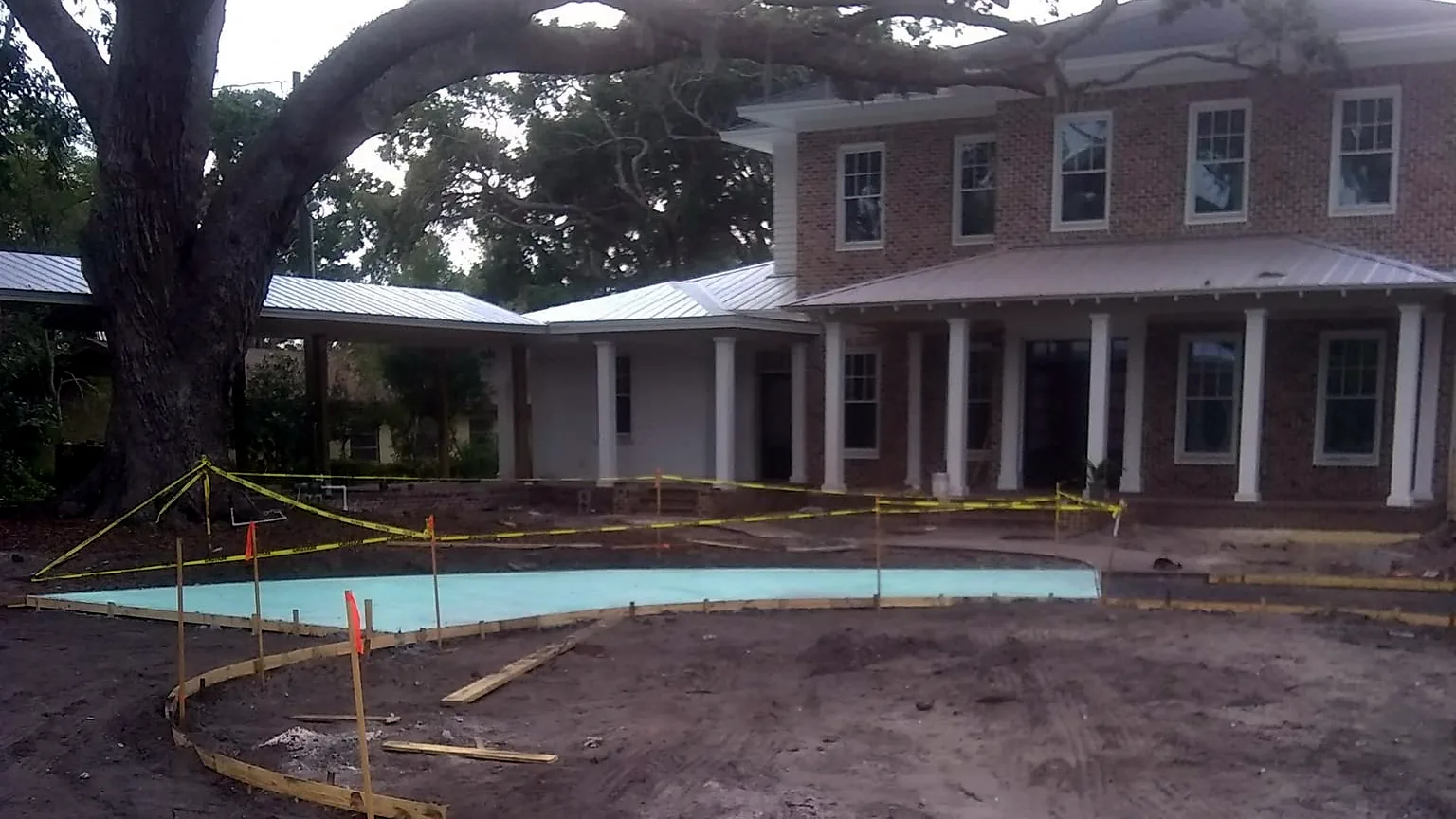 Wood forms staked out for a curved concrete driveway in front of a two-story brick house, masonry