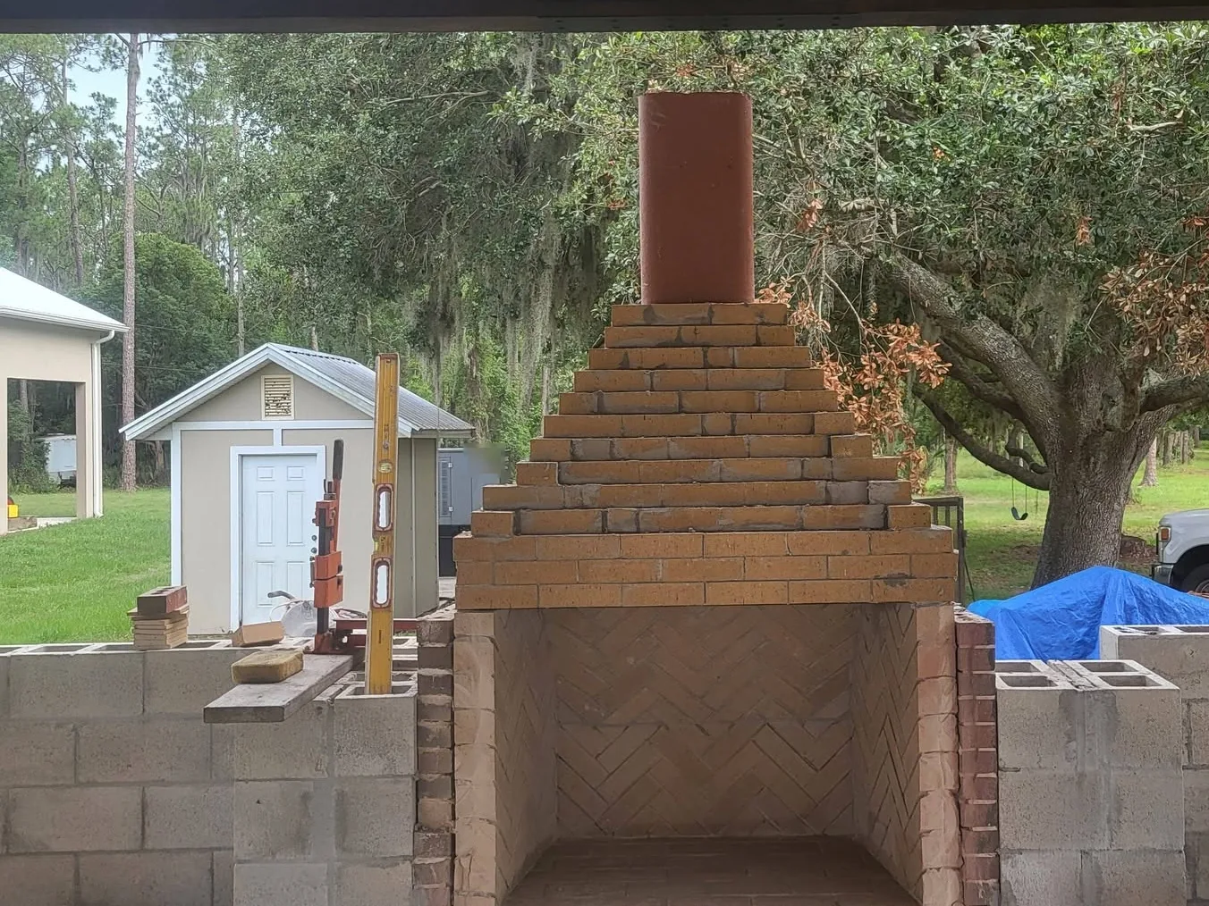 Outdoor fireplaces: masonry fireplace going up under a timber pavilion, with a herringbone firebrick firebox and a stepped firebrick smoke chamber on a concrete block core
