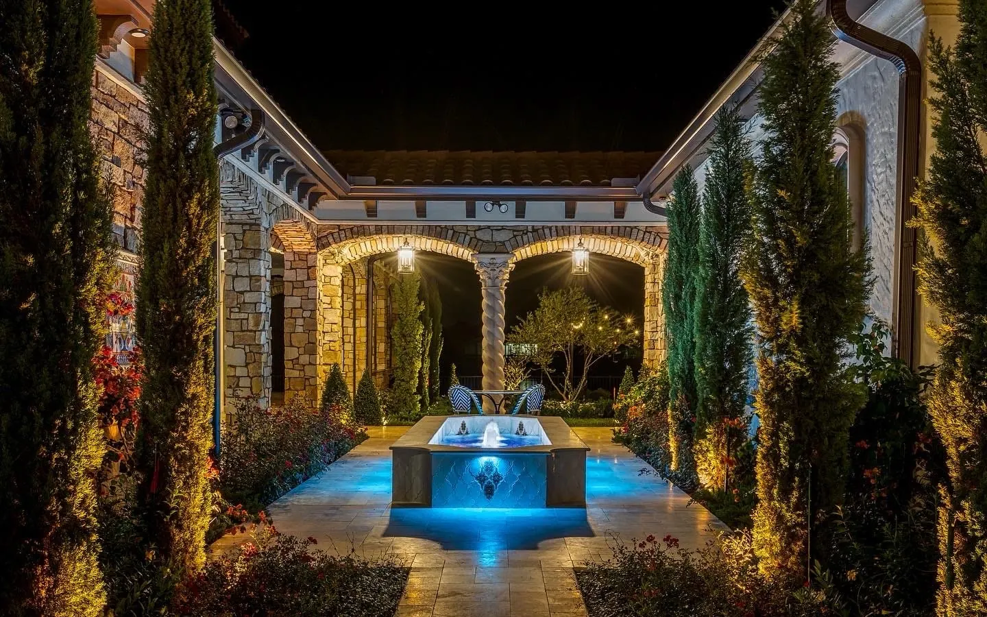 Stone masonry: natural stone arches and columns around a courtyard with a lit fountain at night
